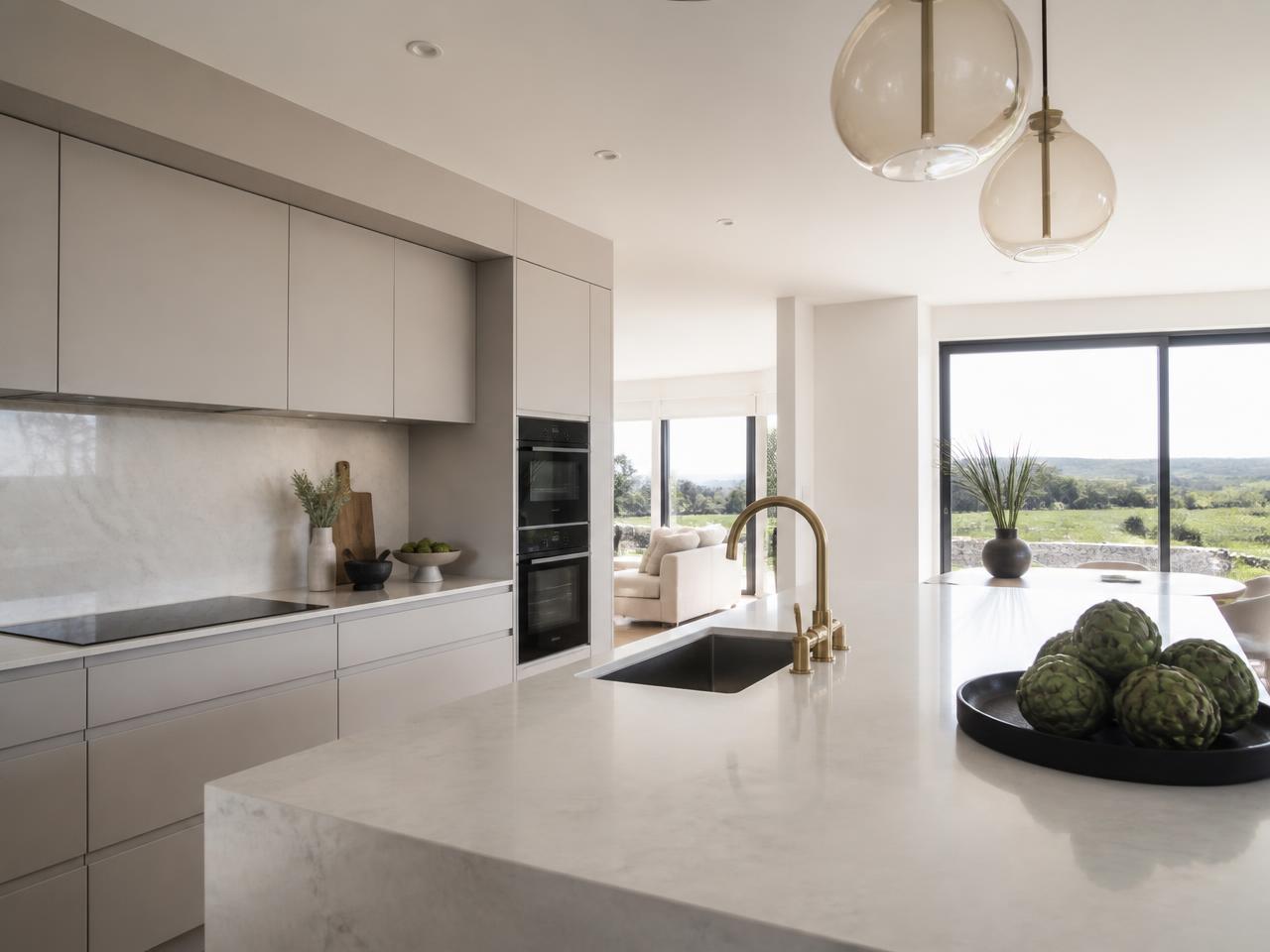 Handleless contemporary kitchen in soft white and warm grey with a refined quartz worktop